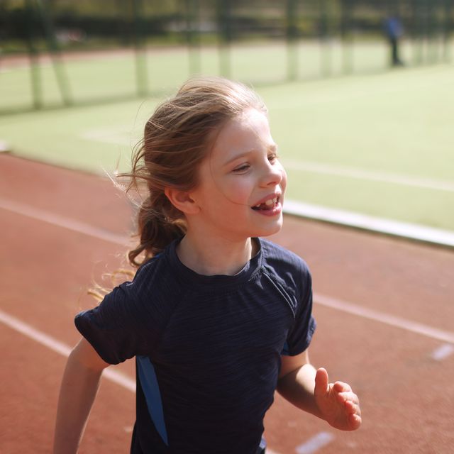 portrait of a young girl racing on an athletics track