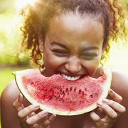 portrait of a young woman eating watermelon on a sunny day, backlit