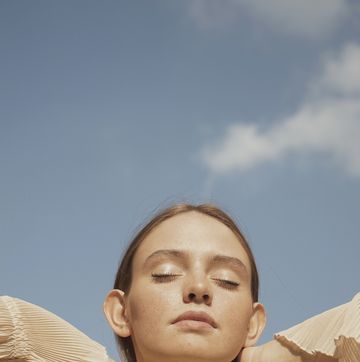 portrait of a young woman with eyes closed against sky