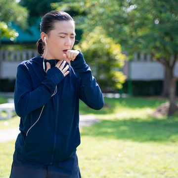 portrait of asian woman wearing earphones listening to music was sick with fever at park