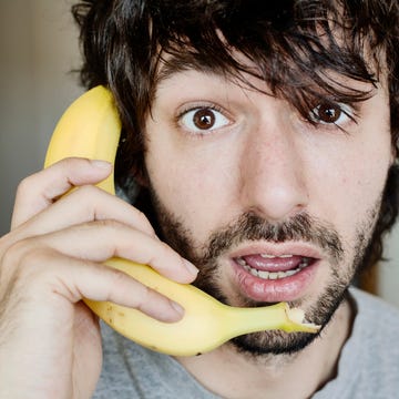 Portrait of astonished young man telephoning with banana