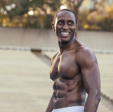 portrait of athletic shirtless man standing on sports field