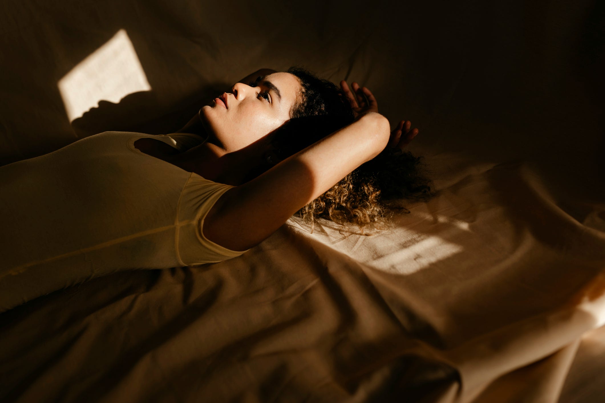 portrait of attractive young woman lying in bed in sunlight