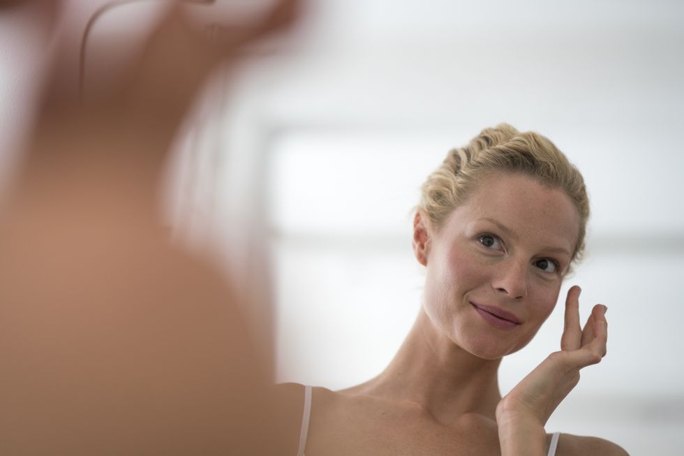 portrait of beautiful blond woman applying eye cream