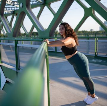 portrait of beautiful young overweight woman outdoors on bridge in city, doing exercise