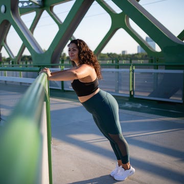 portrait of beautiful young overweight woman outdoors on bridge in city, doing exercise