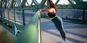 portrait of beautiful young overweight woman outdoors on bridge in city, doing exercise