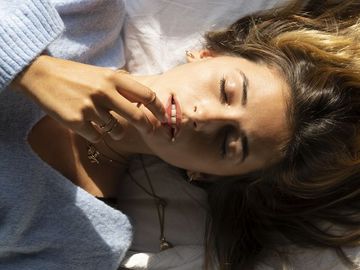 portrait of beautiful young woman lying in bed with closed eyes