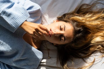 portrait of beautiful young woman lying in bed with closed eyes