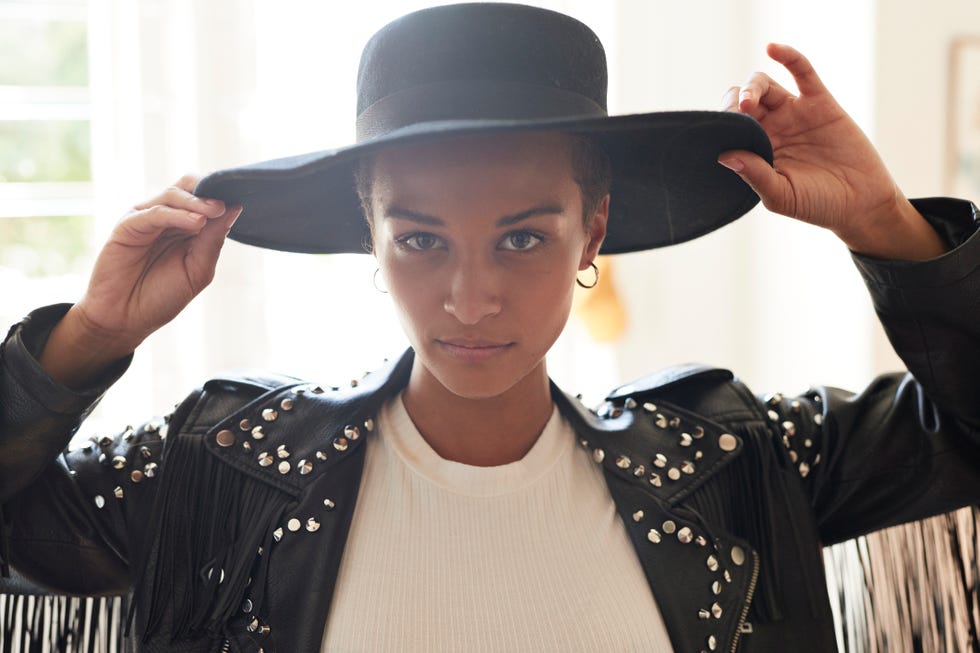portrait of confident young woman holding black hat