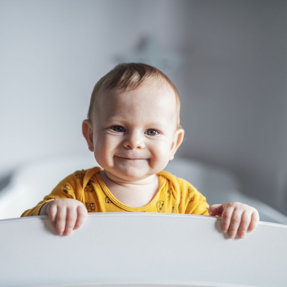 portrait of cute little boy peeking through his crib.