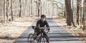 portrait of cyclist with bicycle standing on road at forest