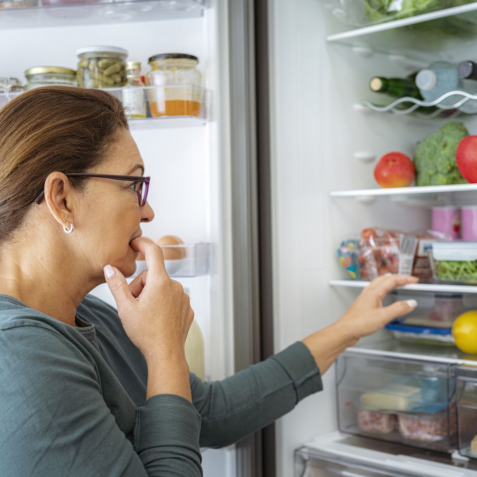 portrait of dubitative woman looking inside the fridge
