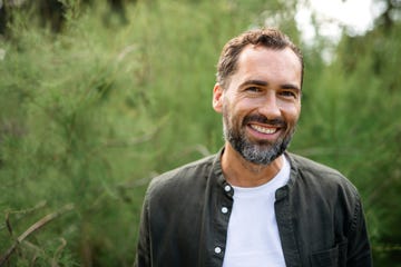 portrait of happy mature man resting outdoors in park, looking at camera