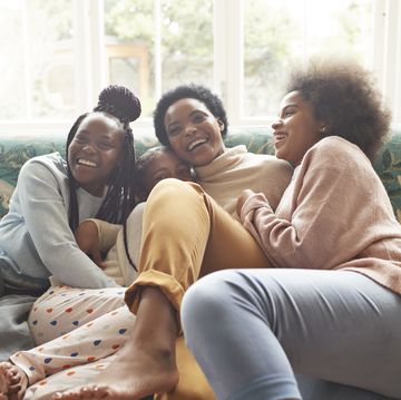 portrait of happy woman embracing girls at home