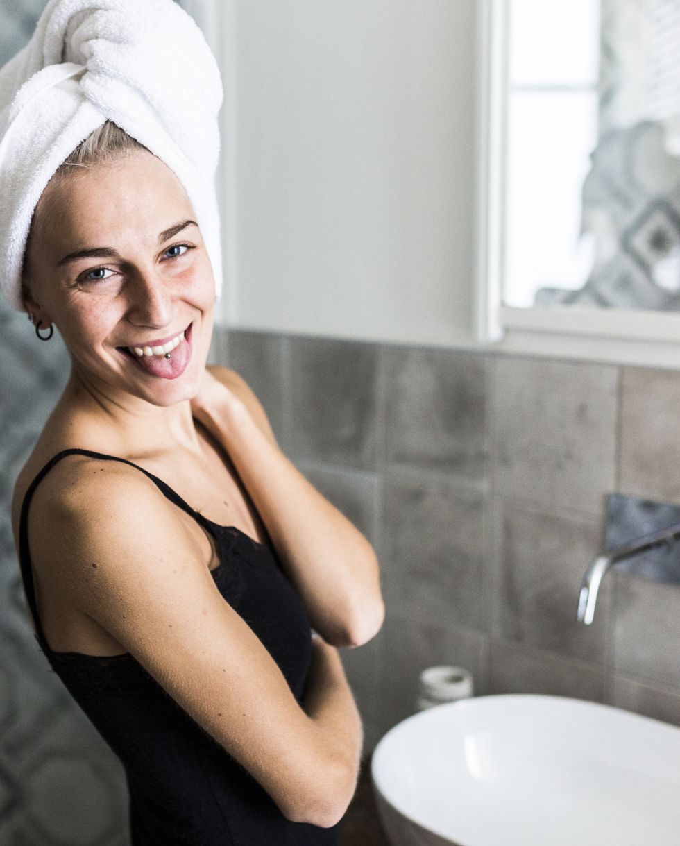Portrait of happy young woman with hair wrapped in a towel in bathroom