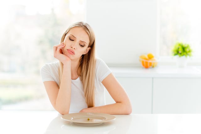 portrait of irritated beautifiul teenager disappointed teen frustrated have lunch sit table touch chin tired unhealthy dressed trendy outfit in kitchen