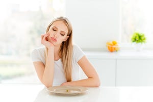 portrait of irritated beautifiul teenager disappointed teen frustrated have lunch sit table touch chin tired unhealthy dressed trendy outfit in kitchen