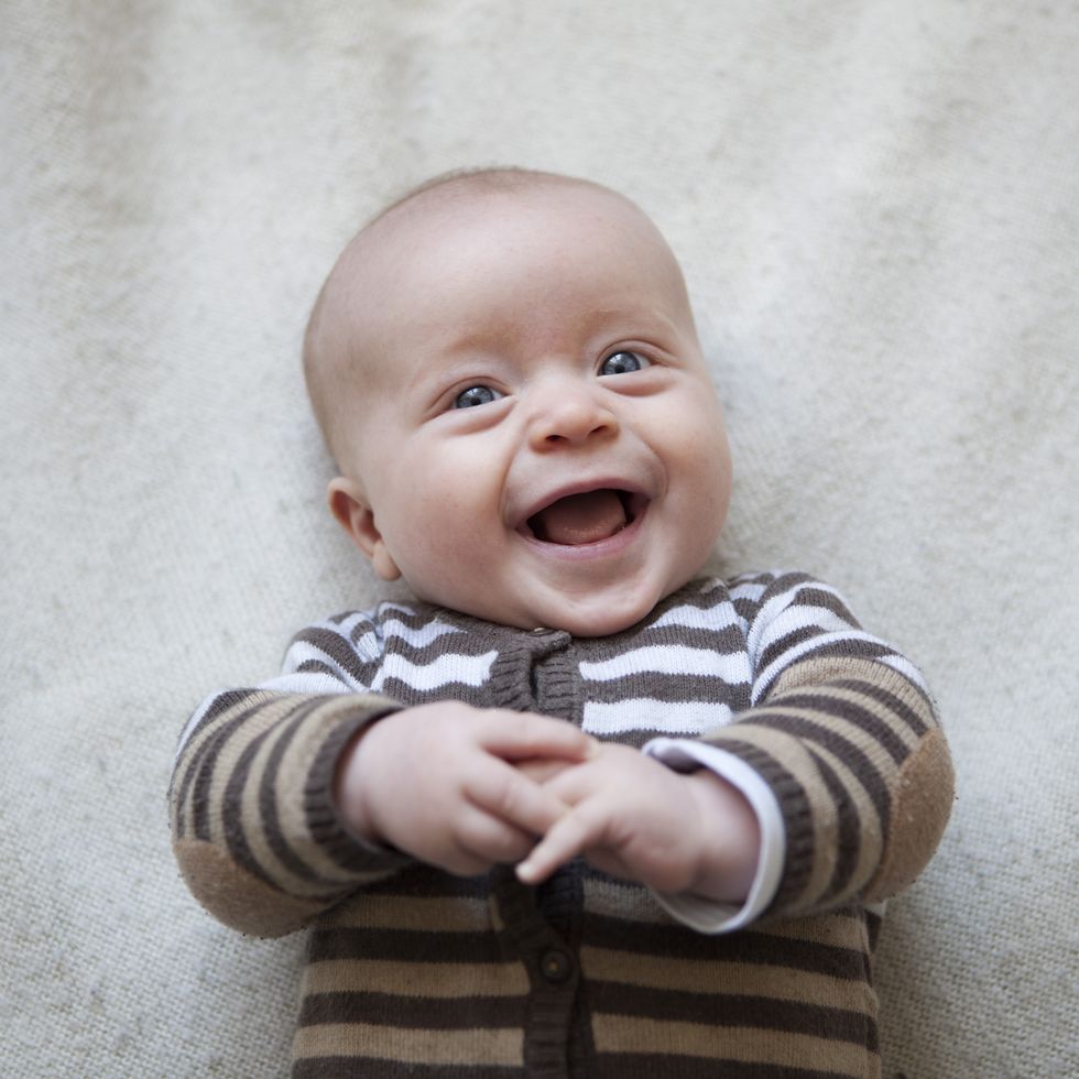 portrait of laughing baby boy lying on blanket