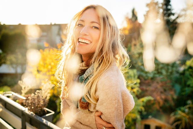 portrait of laughing blond mature woman on balcony at autumn
