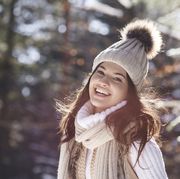 portrait of laughing young woman wearing knitwear in winter forest