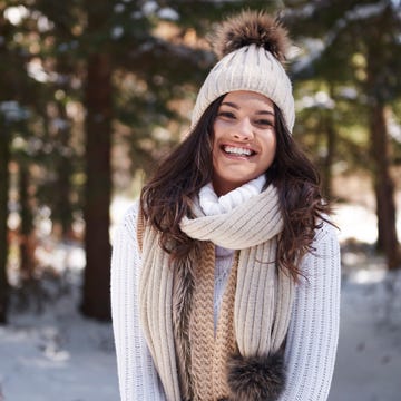 Portrait of laughing young woman wearing knitwear in winter forest