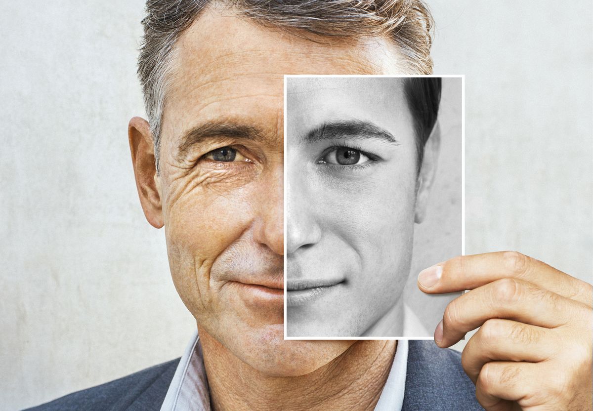 portrait of man holding younger black and white photo of himself
