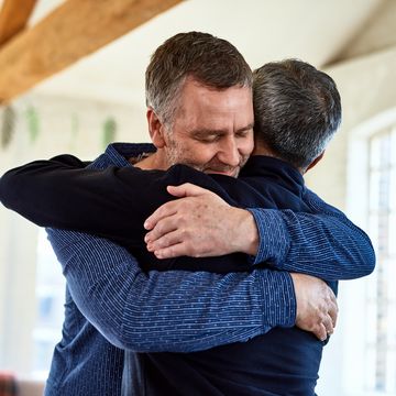 portrait of mature friends embracing with arms around each other