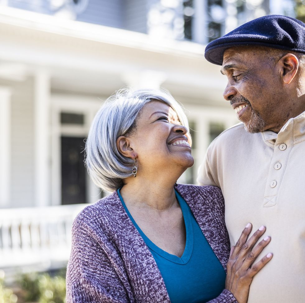 portrait of senior couple in front of suburban home