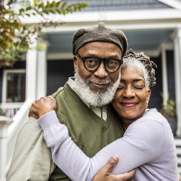portrait of senior husband and wife in front of suburban home