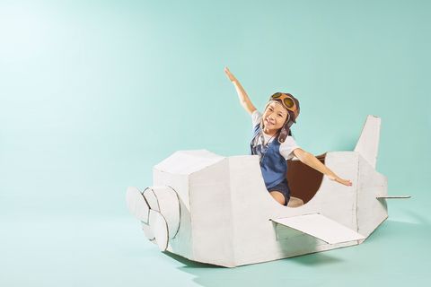 a child pretending to fly a cardboard plane