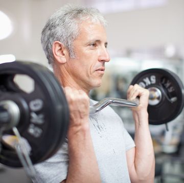 portrait of smiling man holding barbell in gymnasium