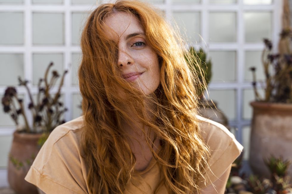 portrait of smiling redheaded young woman on terrace