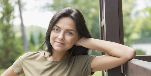 Portrait of smiling woman leaning on railing at yard