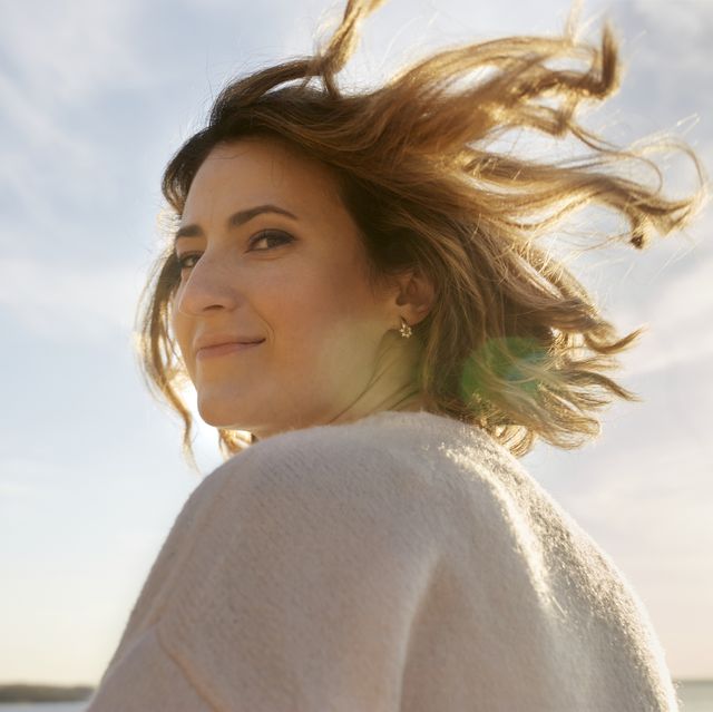 portrait of smiling woman with tousled hair at sunset