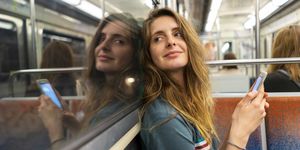 Portrait of smiling young woman and her mirror image in underground train