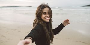 Portrait of smiling young woman holding hands on the beach