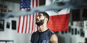 portrait of sweating male boxer listening to trainer during workout in boxing gym