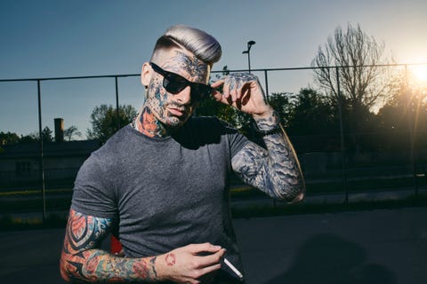 portrait of tattooed young man wearing sunglasses smoking a cigarette