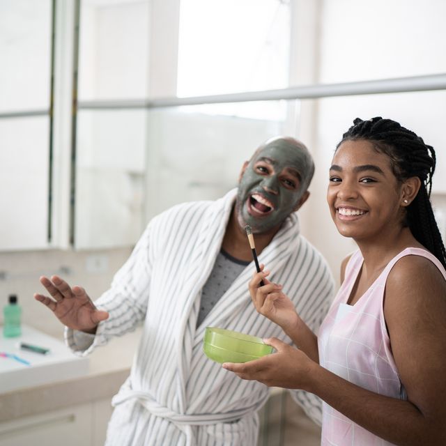 portrait of teenager girl applying facial mask on her father clay mud