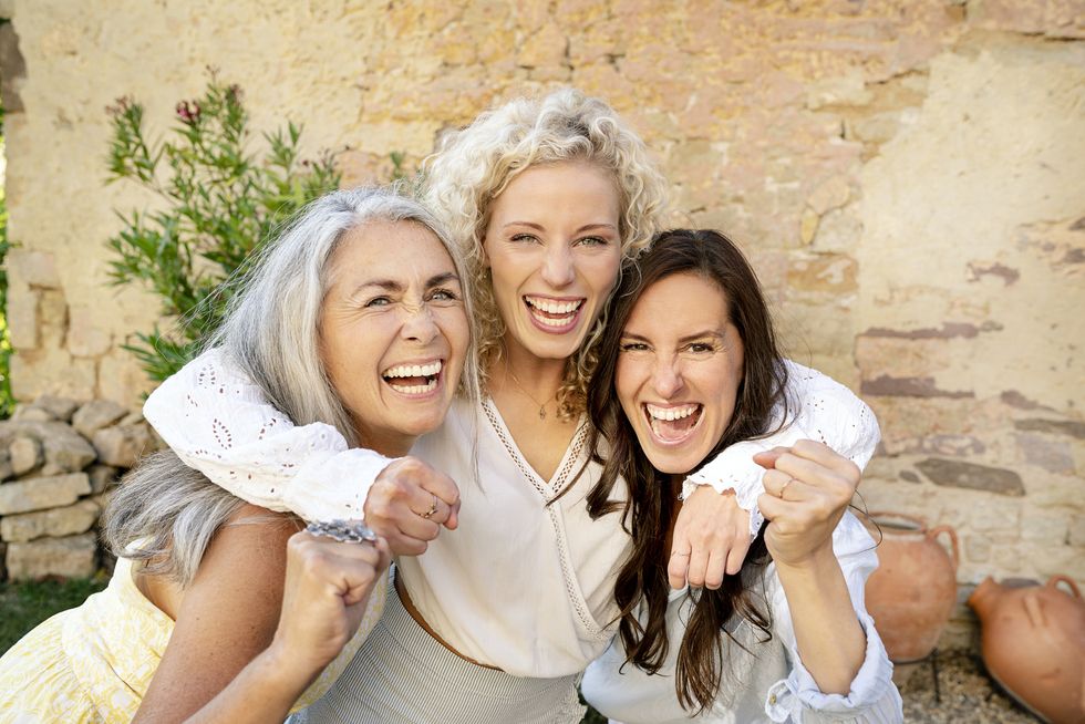 Portrait of three excited women of different age embracing and cheering