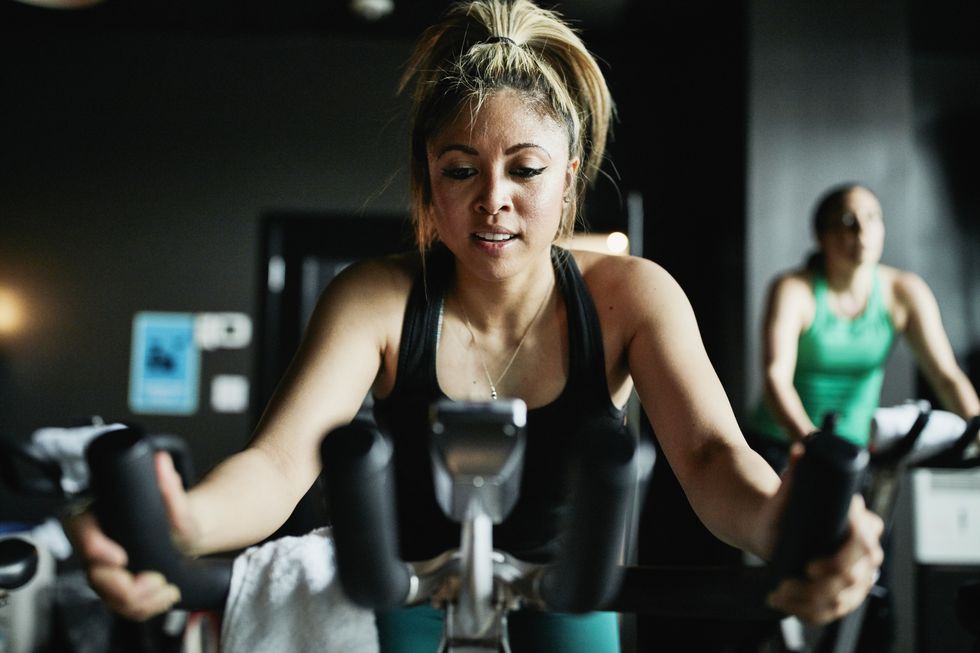 Portrait of woman riding indoor bike during class in cycling studio