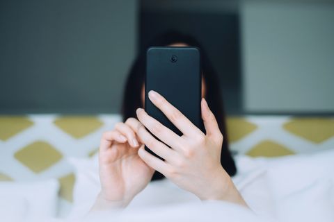 Portrait of woman using mobile phone while lying on bed