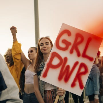 portrait of women protesting with friends for human rights in city against sky