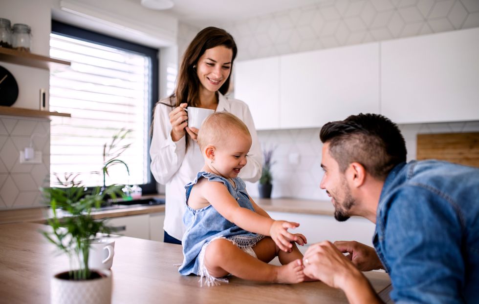 portrait of young couple with toddler girl standing indoors in kitchen at home