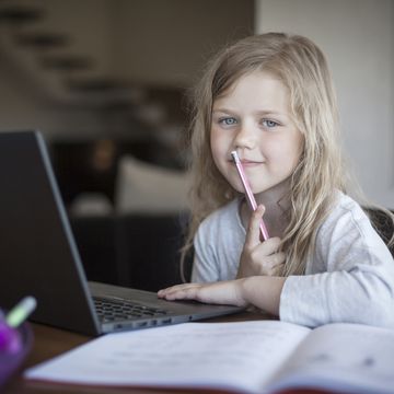 Portrait of young girl doing her school work with laptop