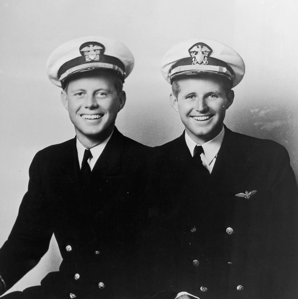 john f kennedy and joseph kennedy jr sit next to each other and smile in navy uniforms and hats