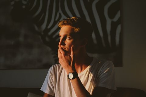 portrait of young man sitting against wall at home