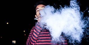 Portrait Of Young Man Smoking Electronic Cigarette At Night