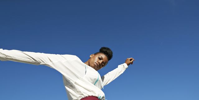 Portrait of young sportswoman against clear blue sky